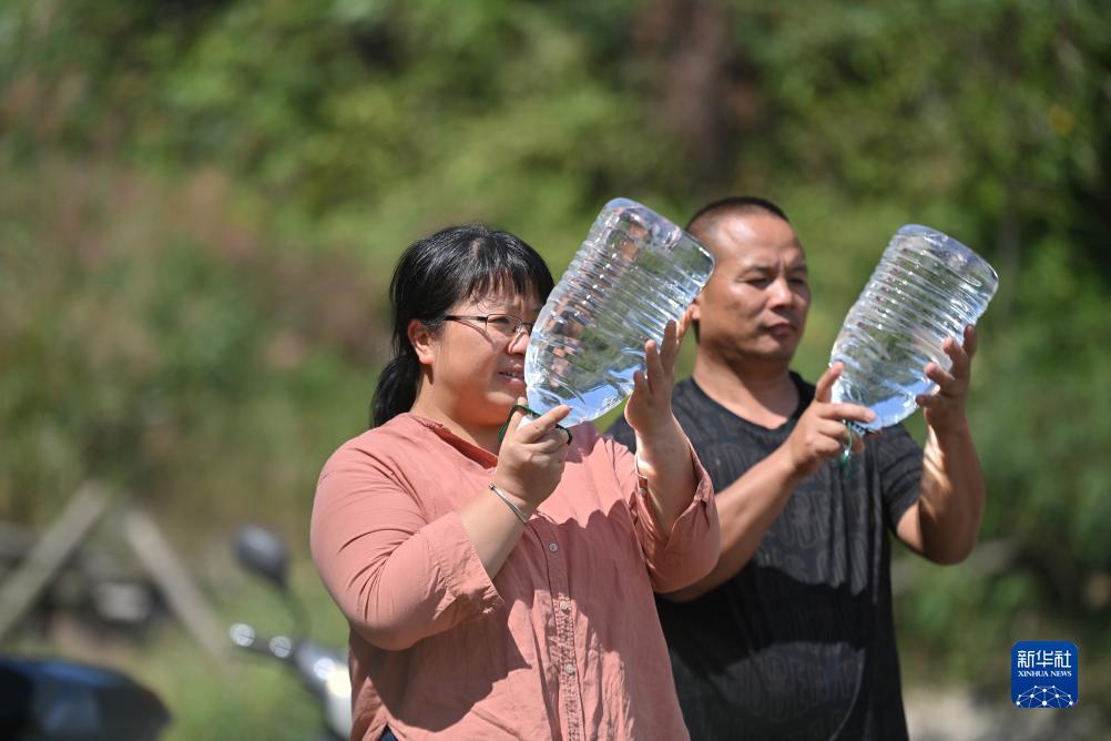 楊寧（左）在查看村民剛剛采集的水樣，為山泉水引水工程做準備（10月8日攝）。新華社記者 黃孝邦 攝